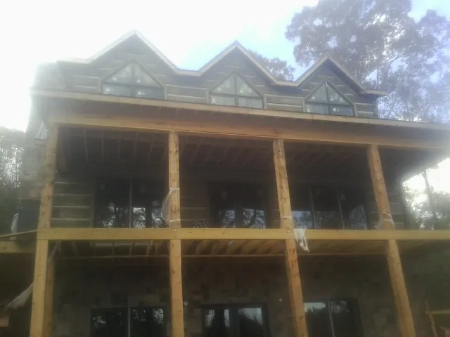 Dormers and porch framing on a large log home under construction — Roof Coating work by our crew in San Tan Valley