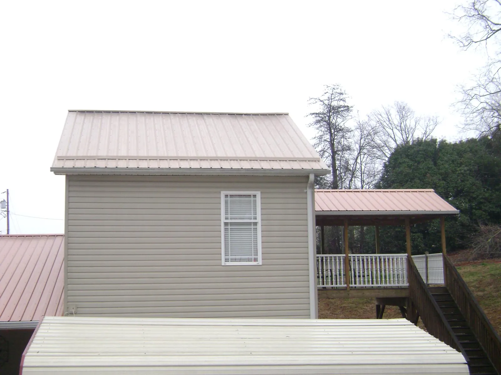 Tan metal roofs on a two story addition and attached porch, from a Roof Replacement job in San Tan Valley