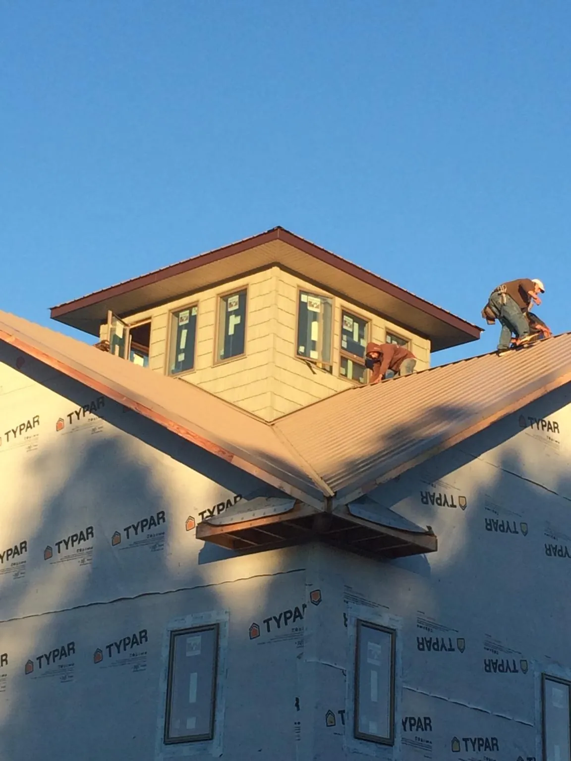 Roofers working around a rooftop cupola on a new metal roof at sunset — Roof Waterproofing in San Tan Valley by Roofing Brothers